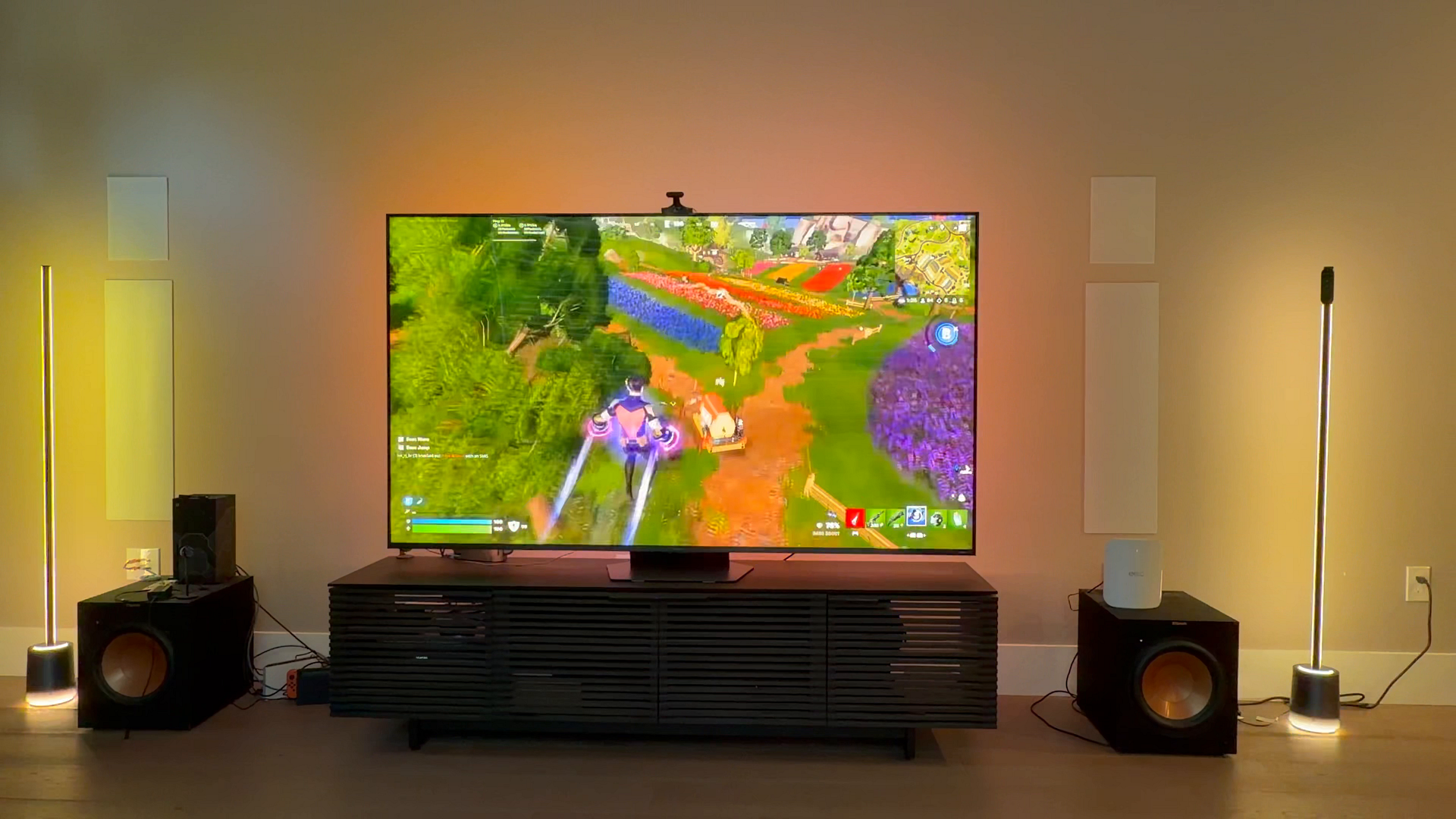 A large TV displaying a video game while synced with two vertical Govee floor lamps on either side
